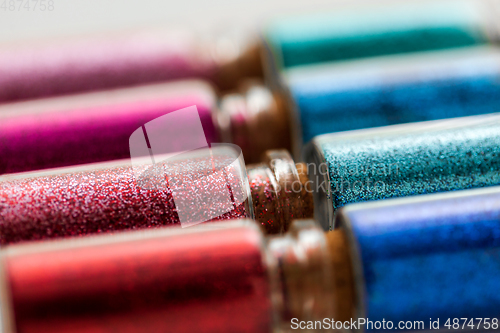 Image of set of different glitters in small glass bottles