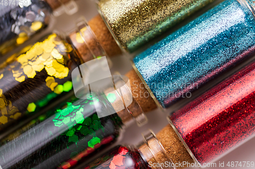 Image of set of different glitters in small glass bottles
