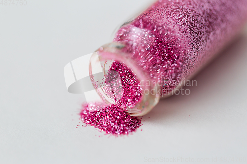 Image of pink glitters poured from small glass bottle