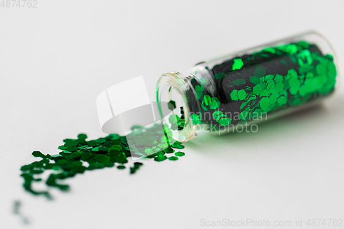 Image of green glitters poured from small glass bottle