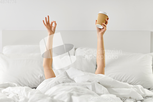 Image of woman with cup of coffee lying in bed showing ok