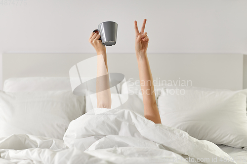 Image of woman with coffee lying in bed showing peace