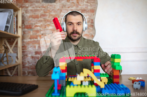 Image of Man giving online lesson with constructor at home. Recording teacher\'s tutorial on camera for kids. Digitalization, remote education