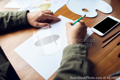 Image of Close up of man drawing with paints and pencils at home. Remote education, creative occupation, art therapy