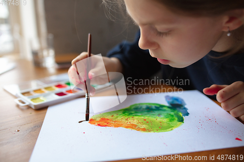 Image of Girl drawing with paints and pencils at home, watching teacher\'s tutorial on laptop. Digitalization, remote education