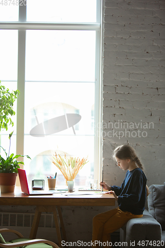 Image of Girl drawing with paints and pencils at home, watching teacher\'s tutorial on laptop. Digitalization, remote education