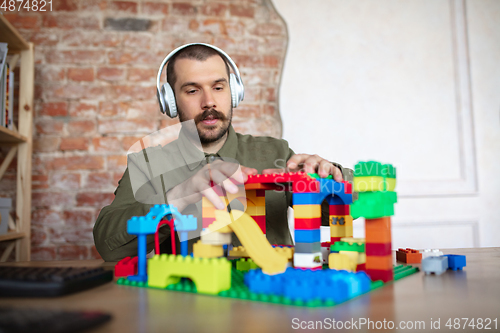 Image of Man giving online lesson with constructor at home. Recording teacher\'s tutorial on camera for kids. Digitalization, remote education