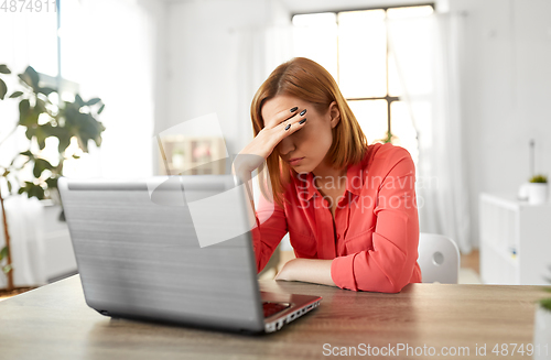 Image of stressed woman with laptop working at home office