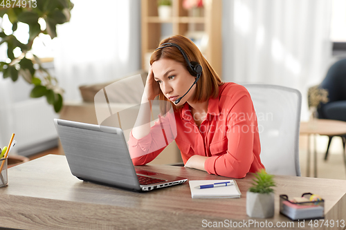 Image of sad woman with headset and laptop working at home