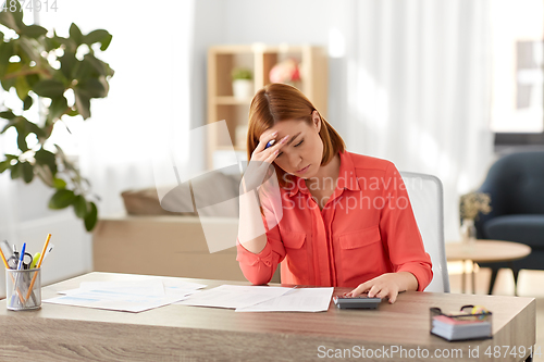 Image of woman with calculator and papers working at home