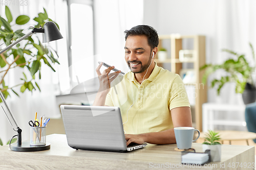 Image of man recording voice on smartphone at home office