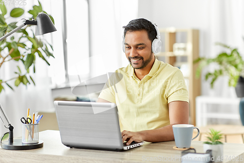 Image of man in headphones with laptop working at home