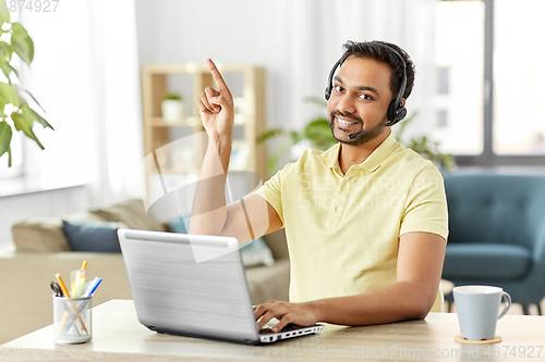 Image of indian man with headset and laptop working at home