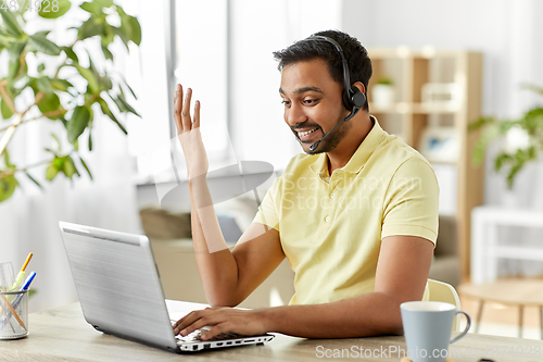 Image of indian man with headset and laptop working at home