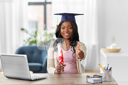 Image of graduate student with laptop and diploma at home