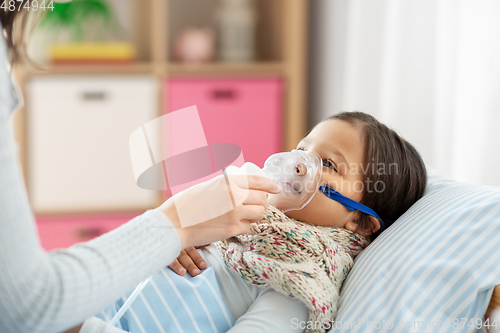 Image of mother and sick daughter with oxygen mask in bed