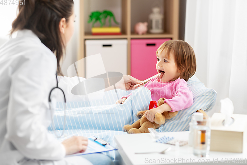 Image of doctor checking sick girl's throat at home