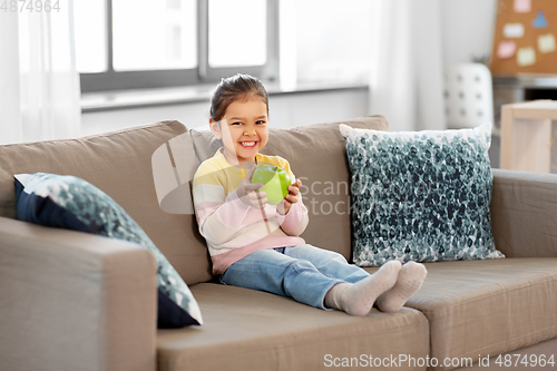 Image of happy little girl with apple sitting on sofa