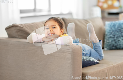 Image of happy smiling little girl lying on sofa at home