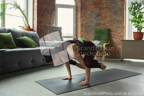 Image of Sporty young woman practicing yoga at home