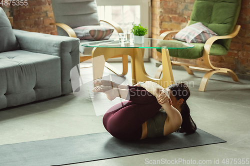 Image of Sporty young woman practicing yoga at home