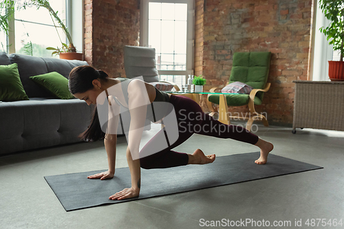 Image of Sporty young woman practicing yoga at home