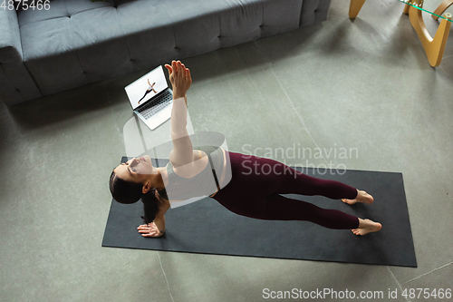 Image of Sporty young woman taking yoga lessons online and practice at home