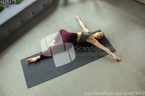 Image of Sporty young woman practicing yoga at home