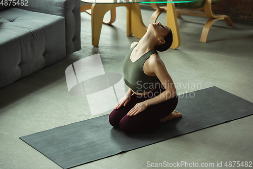 Image of Sporty young woman practicing yoga at home