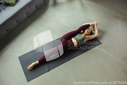 Image of Sporty young woman practicing yoga at home