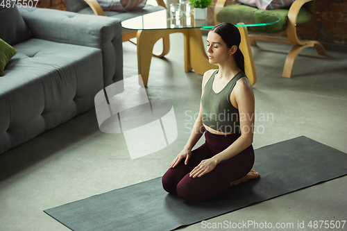 Image of Sporty young woman practicing yoga at home