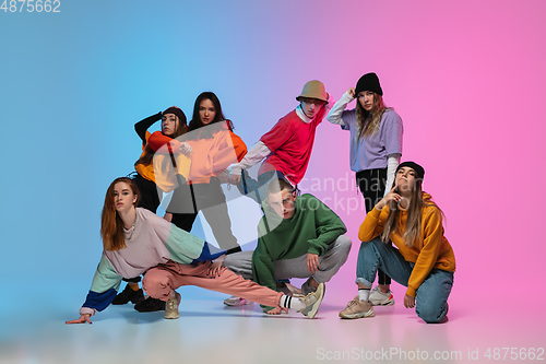 Image of Group of dancers, boys and girls dancing hip-hop in stylish clothes on gradient studio background in neon light.