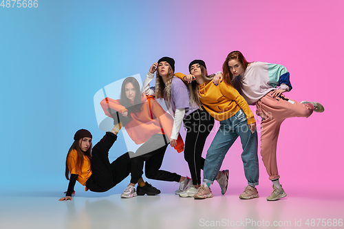 Image of Group of dancers, boys and girls dancing hip-hop in stylish clothes on gradient studio background in neon light.