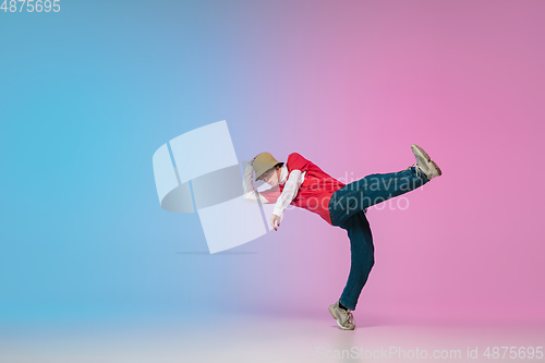 Image of Boy dancing hip-hop in stylish clothes on gradient background at dance hall in neon light.