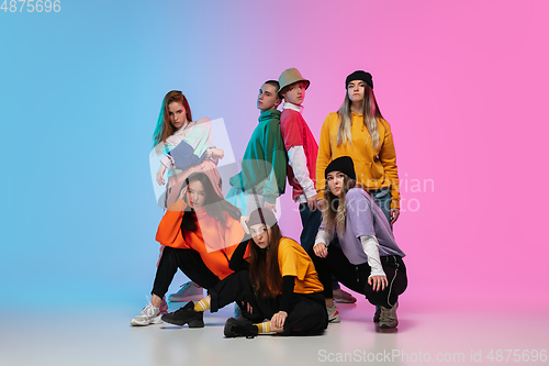 Image of Group of dancers, boys and girls dancing hip-hop in stylish clothes on gradient studio background in neon light.