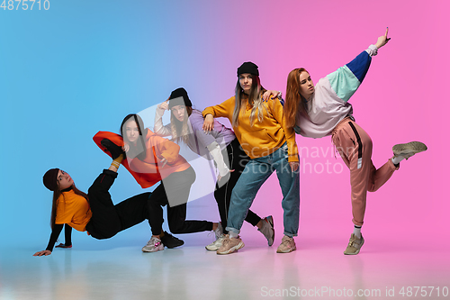 Image of Group of dancers, boys and girls dancing hip-hop in stylish clothes on gradient studio background in neon light.