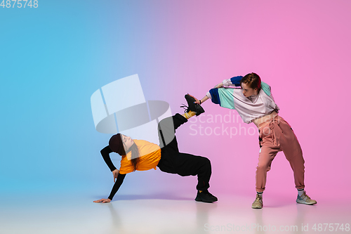 Image of Girls dancing hip-hop in stylish clothes on gradient background at dance hall in neon light.