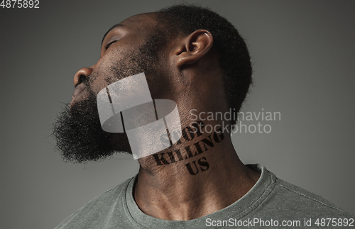 Image of Close up portrait of a black man tired of racial discrimination has tattooed slogan on his neck