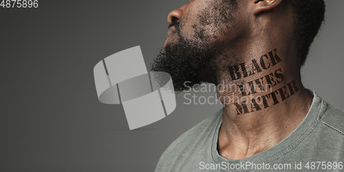 Image of Close up portrait of a black man tired of racial discrimination has tattooed slogan on his neck