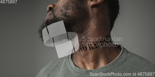 Image of Close up portrait of a black man tired of racial discrimination has tattooed slogan on his neck