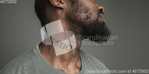 Image of Close up portrait of a black man tired of racial discrimination has tattooed slogan on his neck