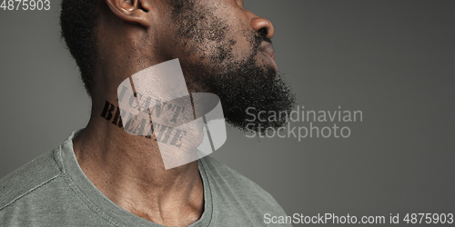 Image of Close up portrait of a black man tired of racial discrimination has tattooed slogan on his neck