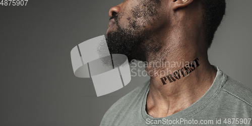 Image of Close up portrait of a black man tired of racial discrimination has tattooed slogan on his neck