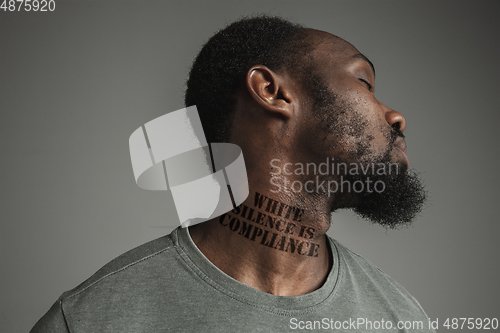 Image of Close up portrait of a black man tired of racial discrimination has tattooed slogan on his neck