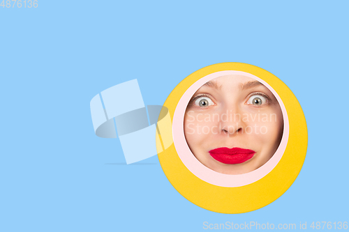 Image of Female face with red lips peeking throught circle in blue background