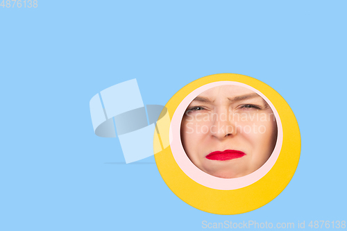 Image of Female face with red lips peeking throught circle in blue background