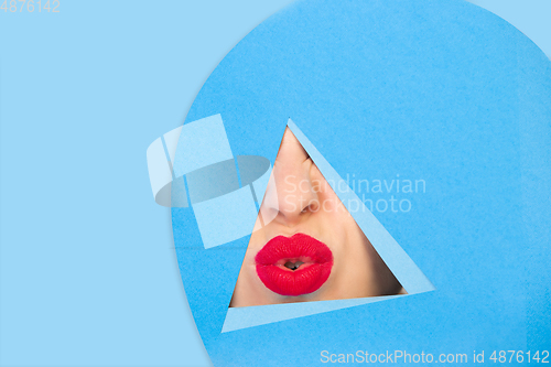 Image of Female red lips peeking throught triangle in blue background