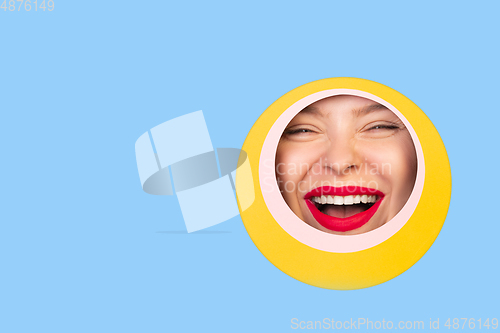 Image of Female face with red lips peeking throught circle in blue background