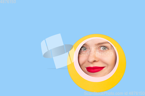 Image of Female face with red lips peeking throught circle in blue background