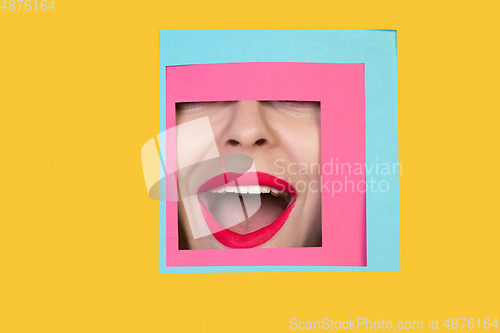 Image of Face of caucasian woman peeking throught square in yellow background